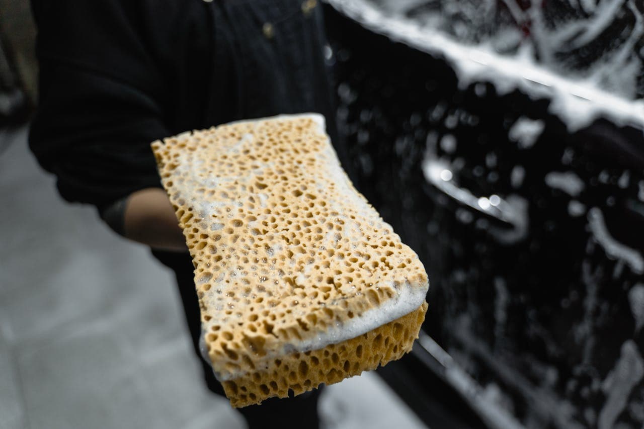 Close-up of sponge with soap foam on car surface